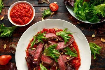 Beef Steak with Romesco sauce, nuts and vegetables on white plate