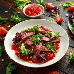 Beef Steak with Romesco sauce, nuts and vegetables on white plate