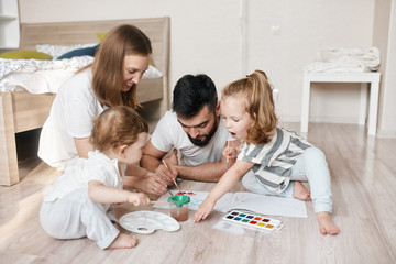 Fototapeta premium young couple enjoying drawing with children in the bedroom. close up photo. creativity concept, family tradition