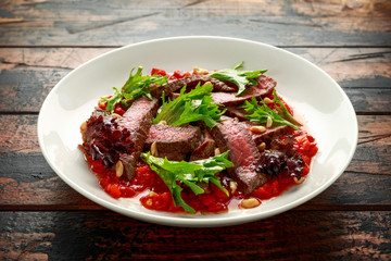 Beef Steak with Romesco sauce, nuts and vegetables on white plate