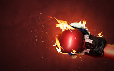 Old red boxing gloves on hot sparkles background with extreme fire flame and fighting fiercely hand...