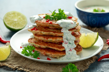 Corn fritters, pancake with dip white sauce, lime and chilli on white plate