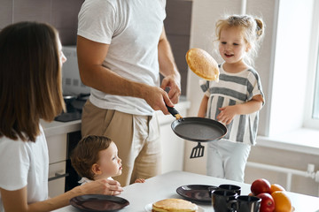 father having fun with pancakes in the kitchen, man boasting about his cooking skills - 292549546