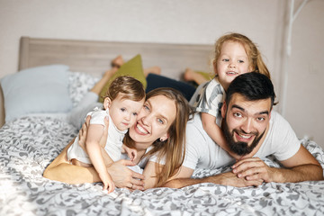 Happy cheerful friendly family lying on the bed, looking at the camera. relationship. close up photo. love, positive emotion and feeling