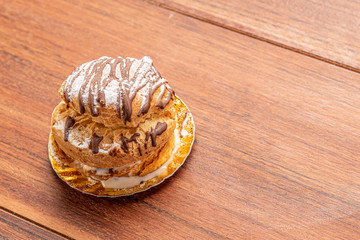 Profiteroles with ice cream and chocolate. Eclairs with black chocolate on wooden background. Traditional French dessert.