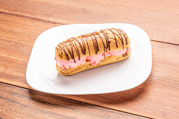 Profiteroles with ice cream and chocolate. Eclairs with black chocolate on wooden background. Traditional French dessert.