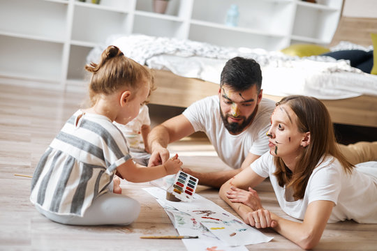 young father , mother and kids mixing colourswhile painting. close up photo