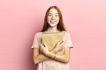 Portrait of intelligent cute clever happy female student wearing casual t-shirt holding exercise...