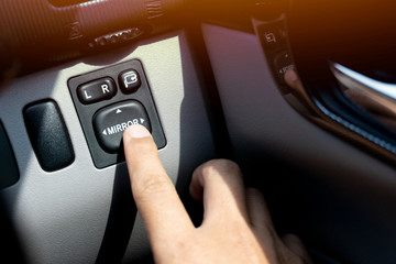 ฺButton control mirror glass adjustment  on the left and right in side car. With finger blurring.