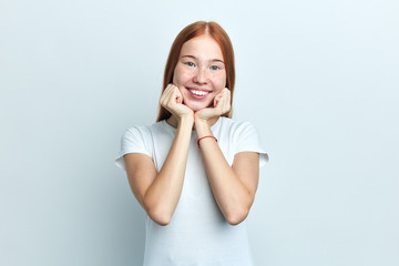 positive female student holds chin, has positive expression, opens eyes, pleasant smile, isolated over white background.close up portrait, positive feeling and emotion