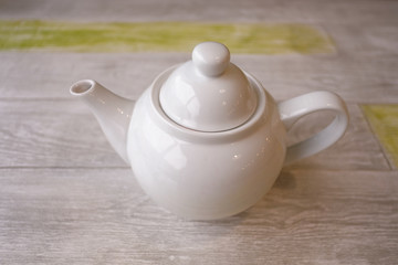 White teapot with tea on a wooden table. Close up