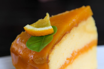 Orange cake in white dish on black background.