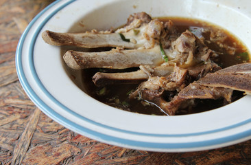 Ribs soup in white bowl on wooden table.