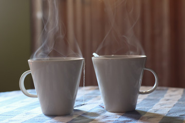 Two mugs of steaming tea