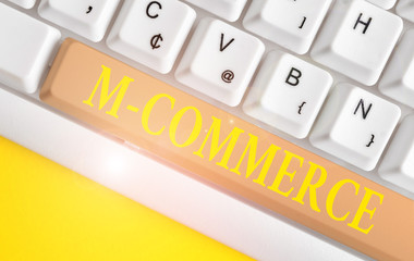 Conceptual hand writing showing M Commerce. Concept meaning commercial transactions conducted electronically by mobile phone White pc keyboard with note paper above the white background