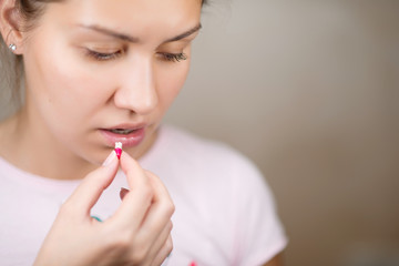 woman hides her look, about to take a colored pill, copy space