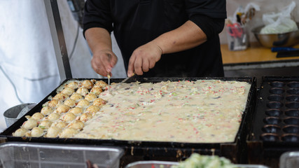 Hand of chef to cooking Takoyaki on hot pan famous food Osaka Japan street food