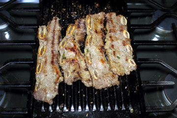Korean style BBQ shortribs, known as Kalbi, on a cast iron grill in a home kitchen.