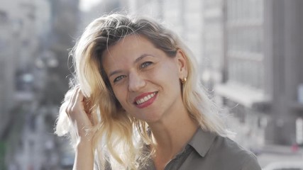 Happy mature woman laughing to the camera joyfully. Beautiful cheerful woman wandering at the city, enjoying warm day outdoors. Travelling, tourism, lifestyle concept