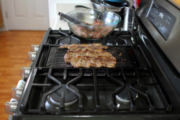 Korean style BBQ shortribs, known as Kalbi, on a cast iron grill in a home kitchen.