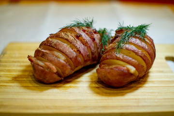 Potato accordion. Garnish potatoes stuffed with bacon and herbs on a wooden stand.