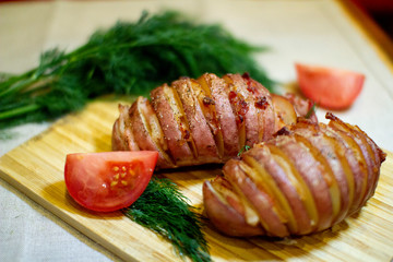 Potato accordion. Garnish potatoes stuffed with bacon and herbs on a wooden stand.