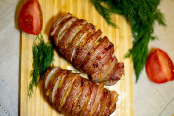 Potato accordion. Garnish potatoes stuffed with bacon and herbs on a wooden stand.