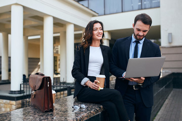 cheerful pensive business woman holding a disposable cup looking at the distance while man is satisfied with successful stock of firms