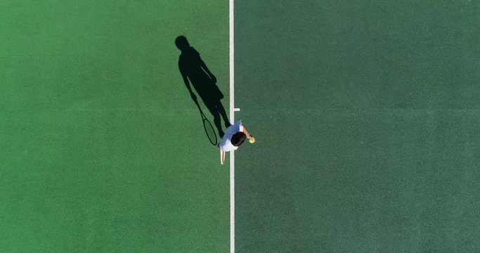 A mixed race tennis player throws the ball high and serves