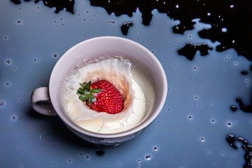 Delicious fresh strawberry falling into splashing milk