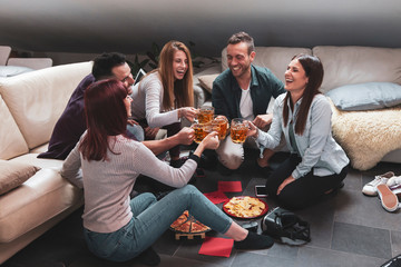 Happy group of friends drinking beer and eating pizza