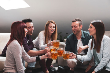 Happy group of friends drinking beer and eating pizza