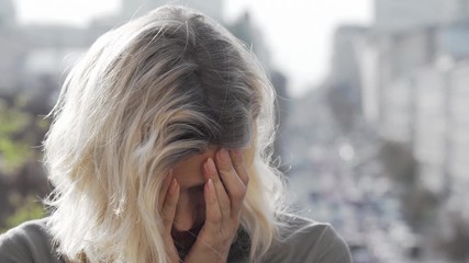 Depressed mature woman looking away thoughtfully. Unhappy woman looking overwhelmed and devastated, urban busy city on background. Sadness, loneliness concept