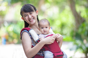 baby feeling happy and smiles with her mother in the garden.Portrait of Asian family.