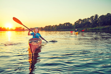 People kayak during sunset in the background. Have fun in your free time. - obrazy, fototapety, plakaty