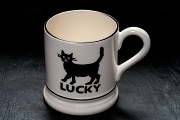 KIEV, UKRAINE - JANUARY 08, 2019:Emma Bridgewater china cup with the image of a black cat and the inscription happy. Editorial image