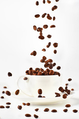 brown coffee, background texture, close-upBackground of coffee beans and coffee Cup and saucer. Coffee beans are poured into the Cup from above.