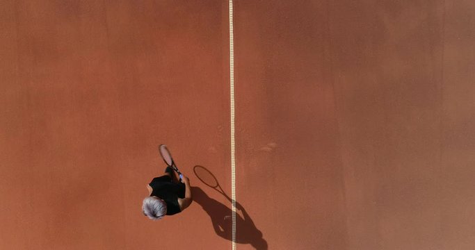A Tennis player throws the tennis ball high to camera and serves.