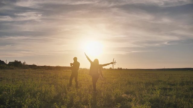 A guy and a girl launch a paralon plane at sunset.