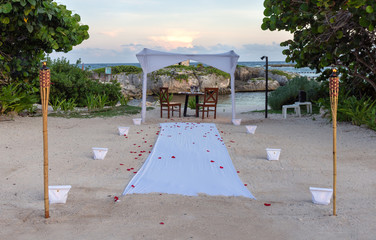 All prepared for a romantic dinner with candles, torches and rose petals on the sea sand beach...