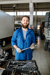 Young bearded master of technical repair standing inside workshop