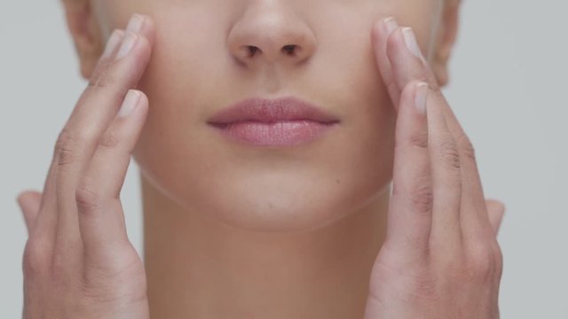 Studio portrait of young, beautiful and natural blond woman applying skin care cream. Face lifting, cosmetics and make-up.