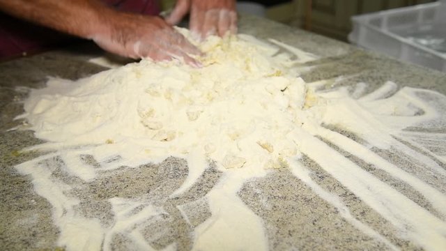 A man prepares to knead the dough for panzerotti or pies: a man kneads dough: in the video, male hands collect flour to make a lump of dough. Durum wheat flour, Senatore Cappelli