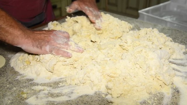 A man prepares to knead the dough for panzerotti pies or bread: a man kneads dough: in the video, male hands collect flour to make a lump of dough. Durum wheat flour, Senatore Cappelli