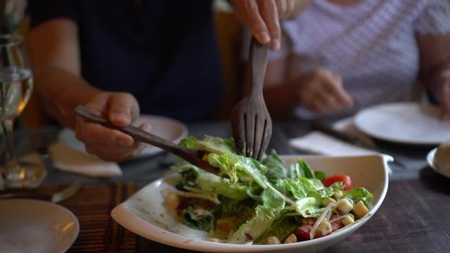 Caesar salad mixing in bowl giving to wife