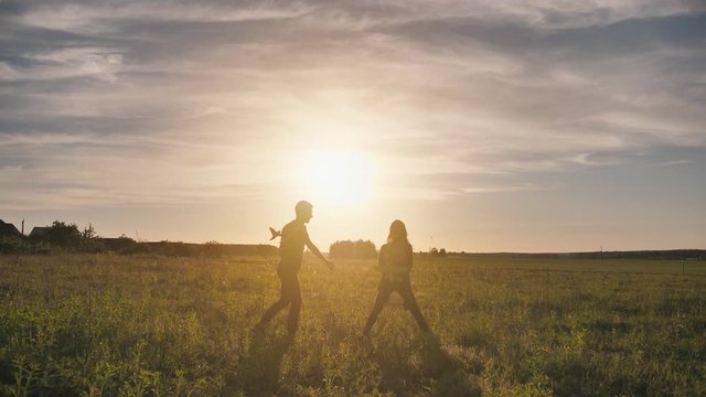 A guy and a girl launch a paralon plane at sunset.