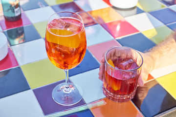 Aperol spritz cocktail and Negroni on colorful tiled table