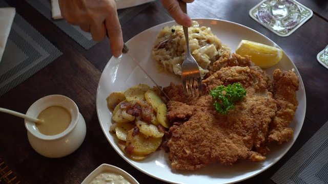 Eating pork Schnitzel Austria cuisine battered meat with  Sauerkraut and potatoes