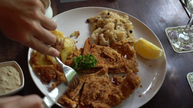 Eating Schnitzel Austria cuisine battered meat with  Sauerkraut and potatoes