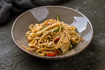chicken wok noodles on dark stone table
